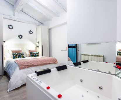 Dormitorio de una de las coquetas suites con jacuzzi privado junto a la cama de este alojamiento.