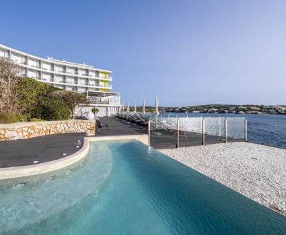 Foto de la piscina infinita con tumbonas y vistas al mar del hotel.