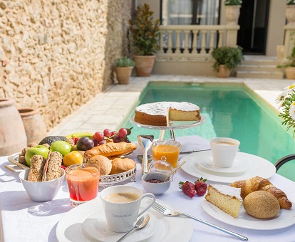 Foto de la mesa para el desayuno con la piscina de fondo y el interior del patio del hotel con mucho encanto y solo para adultos en Palafrugell