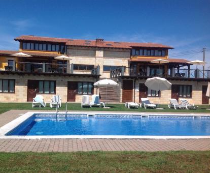 Foto del alojamiento y la piscina con solarium y tumbonas.