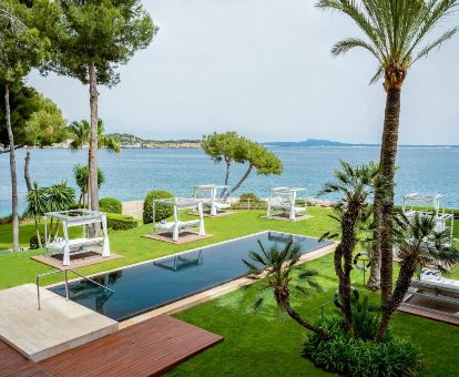 Zona exterior con piscina rodeada de jardines, solarium con camas balinesas y vistas al mar de este maravilloso hotel para parejas.