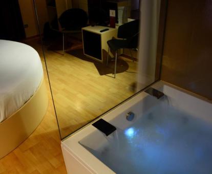 Amplia bañera de hidromasaje privada cerca de la cama de una de las suites.