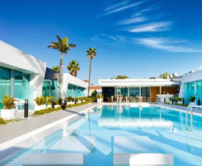 Piscina exterior con tumbonas en el agua de este moderno hotel solo para adultos.