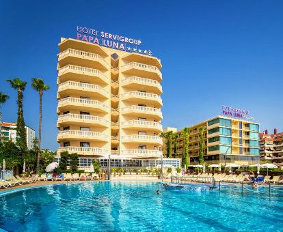 Moderno hotel con una gran piscina al aire libre rodeada de tumbonas, ideal para estancias en pareja.