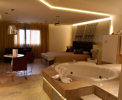 Una de las fabulosas habitaciones con bañera de hidromasaje privada cerca de la cama de este romántico hotel para parejas.