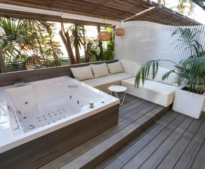 Terraza con bañera de hidromasaje privada y mobiliario exterior de la habitación doble deluxe del hotel.