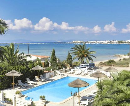 Vista aérea de los exteriores de este hotel en primera línea de playa con piscina rodeada de tumbonas.