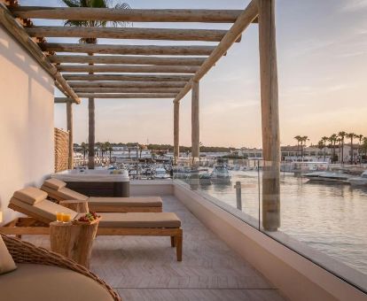 Terraza con mobiliario, bañera de hidromasaje privada y vistas al mar de una de las habitaciones del hotel.