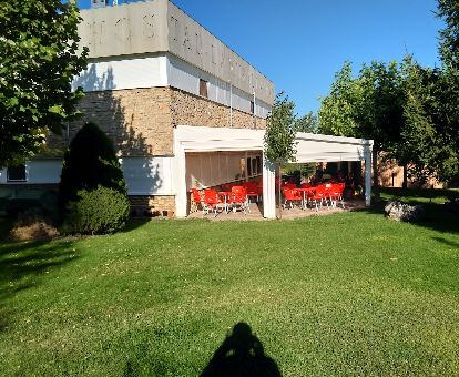 Acogedor hotel con amplios jardines y terraza con mobiliario exterior.