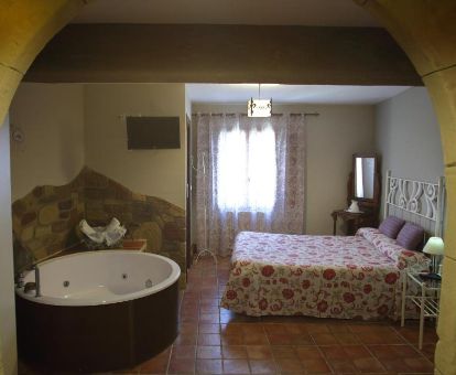 Dormitorio con bañera de hidromasaje privada de uno de los hermosos apartamentos rústicos de este establecimiento.