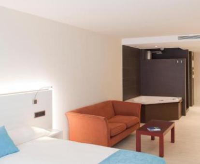 Habitación doble confort con zona de estar y jacuzzi privado para dos personas cerca de la cama.