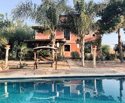 Coqueto hotel ideal para parejas con piscina al aire libre y zona exterior con palmeras.