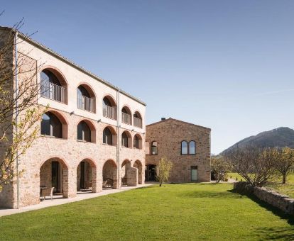 Gran edificio rodeado de vegetación y montañas de este hotel romántico.