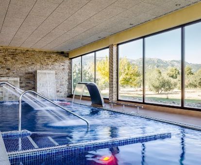 Espacio de bienestar con piscina de hidroterapia y vistas a la naturaleza del hotel.