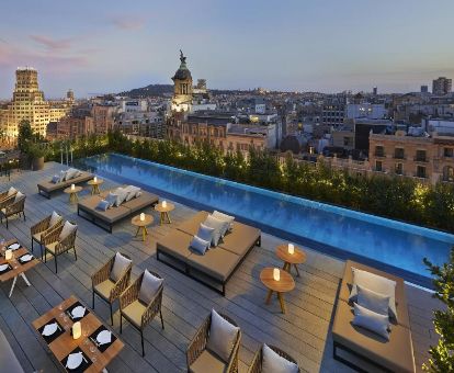 Maravillosa terraza con mobiliario y piscina con vistas a la ciudad de este elegante hotel.