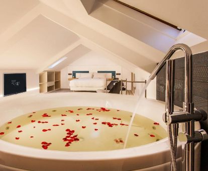 Suite Deluxe con una gran bañera de hidromasaje privada junto a la cama en este moderno hotel ideal para parejas.