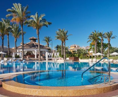 Fabulosa zona exterior con piscinas, tumbonas y palmeras de este moderno hotel ideal para estancias en pareja.
