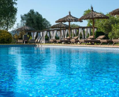 Foto de la piscina rodeada de naturaleza con camas balinesas y tumbonas.