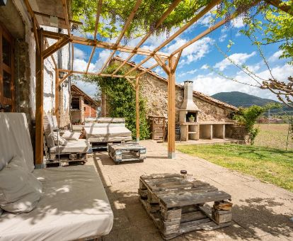 Zona exterior ajardinada con barbacoa y mobiliario de este alojamiento rural.