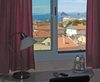 Foto de la ventana con vistas al mar y a la ciudad de una de las habitaciones del alojamiento.