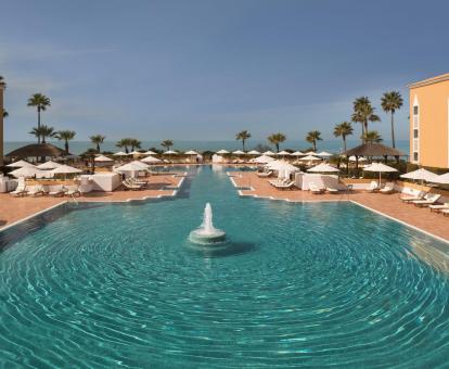 Foto de la piscina del hotel con amplias zonas de tumbonas y vistas al mar.