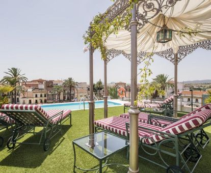 Agradable terraza solarium con mobiliario, piscina y vistas a la ciudad de este elegante hotel.