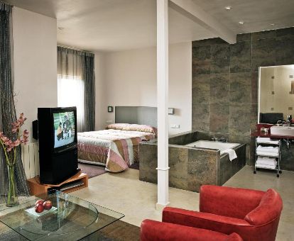 Hermosa suite con bañera de hidromasaje privada junto a la cama y sala de estar de este hotel romántico.