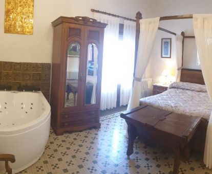 Una de las habitaciones de estilo tradicional con bañera de hidromasaje privada junto a la cama en este acogedor hotel.