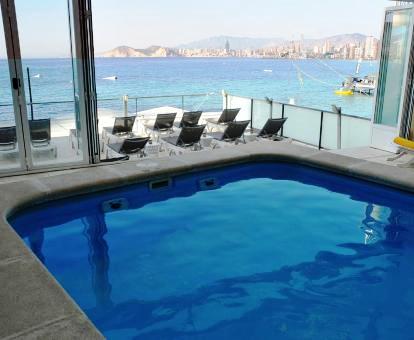 Foto de la piscina cubierta al aire libre con terraza y tumbonas con vistas al mar.