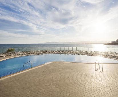 Foto de la amplia piscina con vistas panorámicas al mar y solarium.