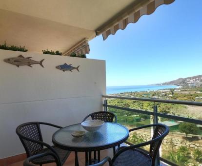 Foto del balcón con comedor y vistas al mar y a los alrededores de este apartamento.