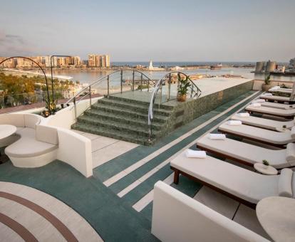 Foto de la terraza del hotel con solarium, piscina exterior y vistas al mar.