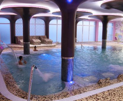 Varias personas disfrutan de la piscina de hidroterapia del centro de bienestar del hotel.