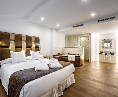 Espectacular suite deluxe con bañera de hidromasaje privada junto a la cama de este hotel romántico ideal para estancias en pareja.
