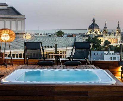 Agradable terraza con mobiliario y jacuzzi con vistas a la ciudad de este elegante hotel.
