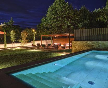 Agradable espacio exterior con jardín, mobiliario y piscina al aire libre de este hotel para parejas.