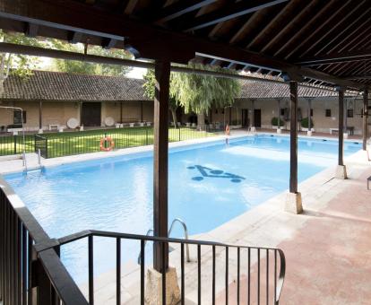 Foto de la piscina del hotel con jardines y tumbonas.