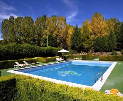 Foto de la piscina al aire libre del hotel rodeada de bellos jardines.