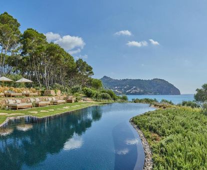 Hermosa zona exterior rodeada de vegetación con piscina al aire libre y vistas al mar de este romántico hotel para parejas.