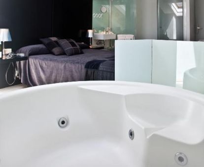 Dormitorio con bañera de hidromasaje privada junto a la cama en este acogedor hotel romántico.