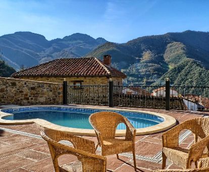 Terraza con piscina exterior y vistas a las montañas de este alojamiento romántico.
