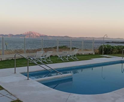 Foto de la piscina con tumbonas y vistas al mar.