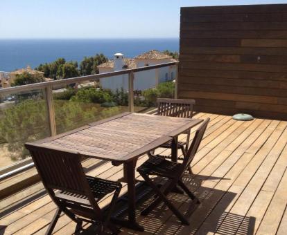 Foto de la amplia terraza con comedor exterior y vistas al mar y a los alrededores de este apartamento.