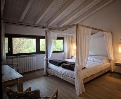 Foto de una de las coquetas habitaciones con cama con dosel y vistas al exterior.