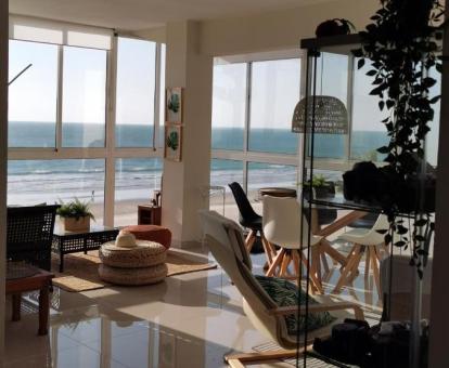 Foto del amplio salón con grandes cristaleras y vistas al mar de este apartamento.