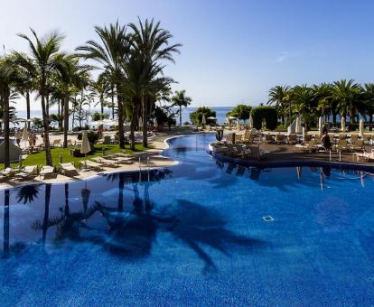 Foto de una de las amplias piscinas del hotel con amplio solarium y vistas al mar.