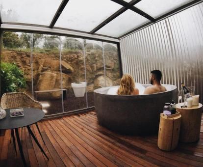 Pareja disfrutando de la zona de bienestar privada con vistas y bañera redonda de una de las habitaciones del hotel.