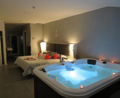 Espectacular habitación doble deluxe de este establecimiento con una gran bañera de hidromasaje privada junto a la cama.