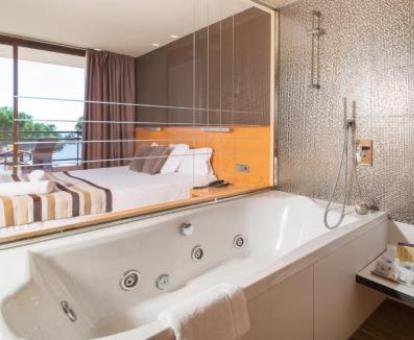 Bañera de hidromasaje privada amplia cerca de la cama de la habitación doble superior de este hotel.