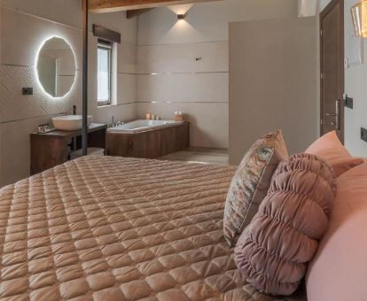Suite Deluxe con bañera de hidromasaje cerca de la cama de este acogedor hotel rural.